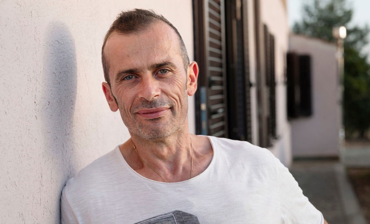 Portretfoto van Andrea, staand buiten zijn huis. Andrea leeft met MS en had graag iets meer willen weten over wat hij kon verwachten van de bijbehorende blaasklachten en darmproblemen. 